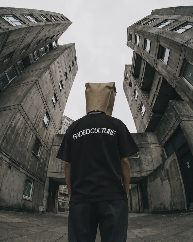 A bag-head in the black Faded Culture tee between concrete towers